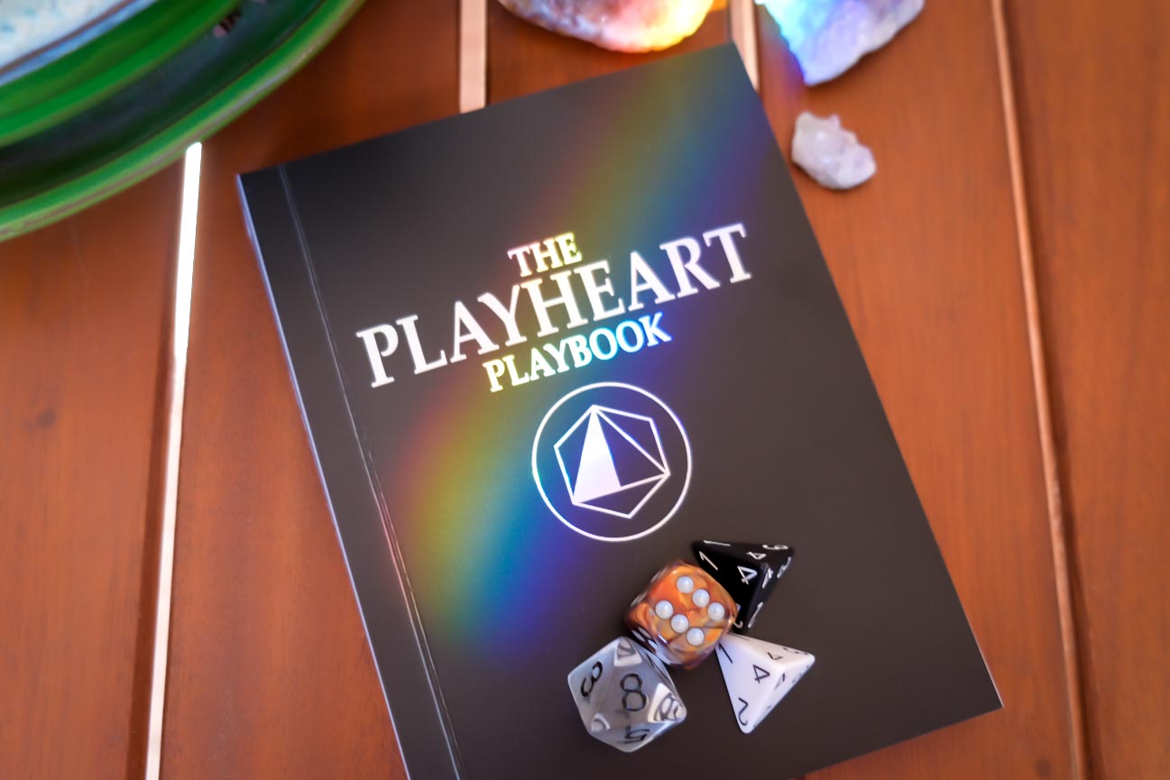 The Playheart Playbook with the four Playheart dice
